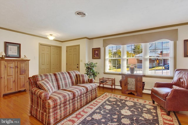 living room featuring light wood finished floors, visible vents, baseboard heating, and crown molding