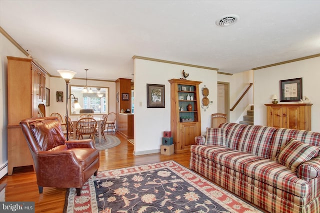 living room with stairway, light wood-type flooring, visible vents, and ornamental molding