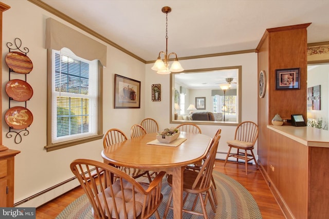 dining area with a baseboard heating unit, crown molding, light wood-style flooring, and baseboards