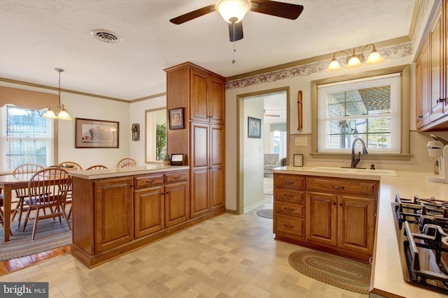 kitchen featuring crown molding, cooktop, light countertops, brown cabinets, and a peninsula