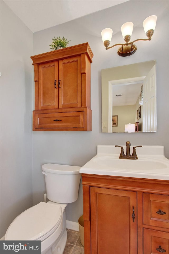 half bath with vanity, tile patterned floors, toilet, and baseboards