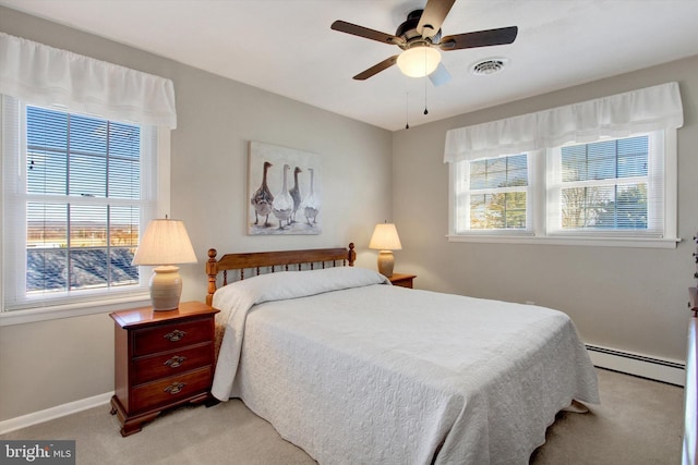 bedroom featuring multiple windows, light colored carpet, visible vents, and baseboard heating