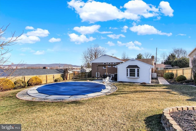 view of pool with a fenced backyard, a yard, an outdoor structure, a fenced in pool, and a patio area