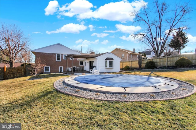 rear view of property with a fenced backyard, a fenced in pool, a patio, and a yard