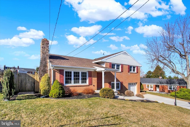 split level home featuring driveway, fence, a garage, brick siding, and a chimney