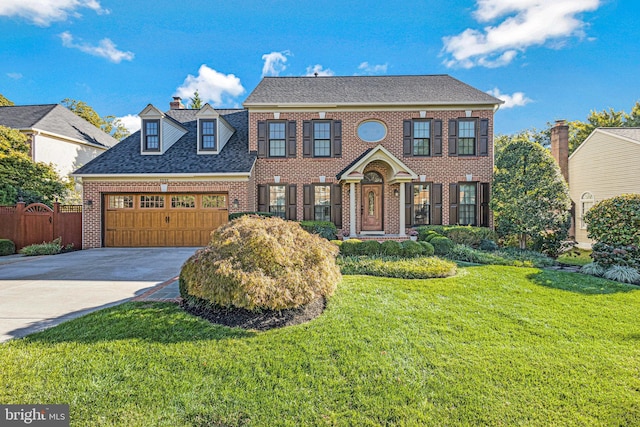 colonial-style house featuring brick siding, a front lawn, fence, concrete driveway, and an attached garage