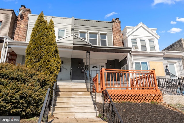 townhome / multi-family property featuring brick siding, covered porch, and a chimney