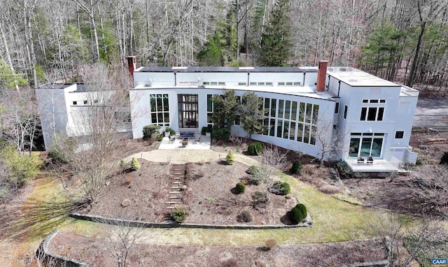 rear view of house with a wooded view, a chimney, and entry steps