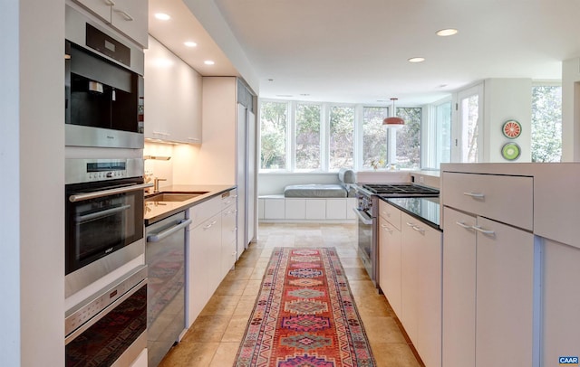 kitchen featuring a sink, white cabinetry, recessed lighting, stainless steel appliances, and hanging light fixtures