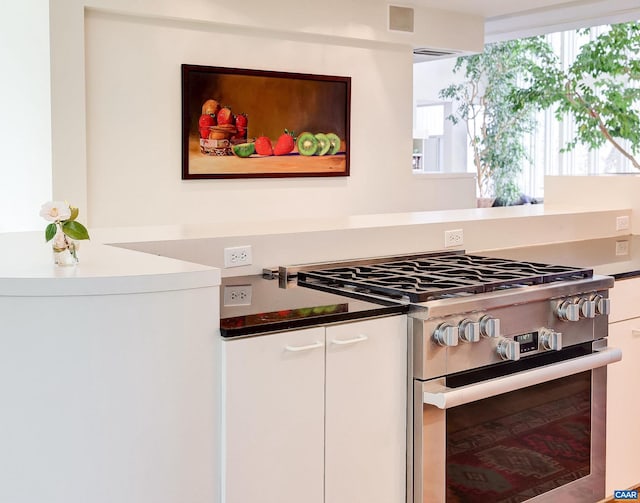 kitchen featuring open shelves, white cabinets, visible vents, and stainless steel gas stove