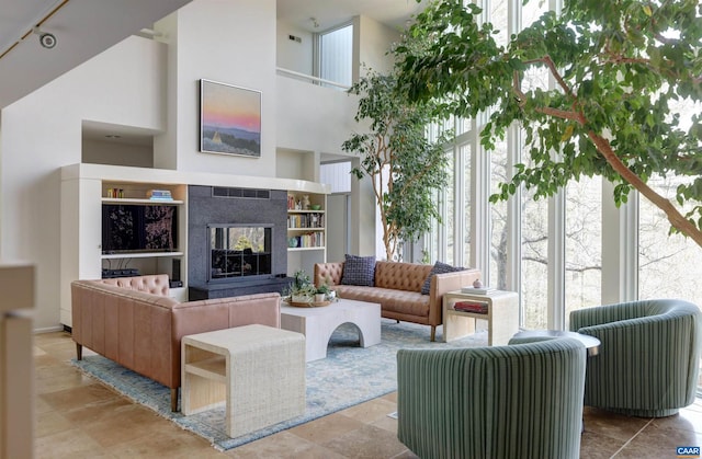 living area with a towering ceiling and a tile fireplace