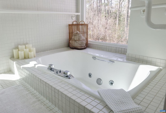 bathroom featuring tile patterned flooring, a tub with jets, and tile walls