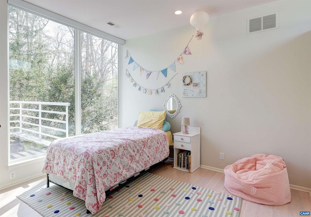 bedroom with multiple windows, wood finished floors, and visible vents