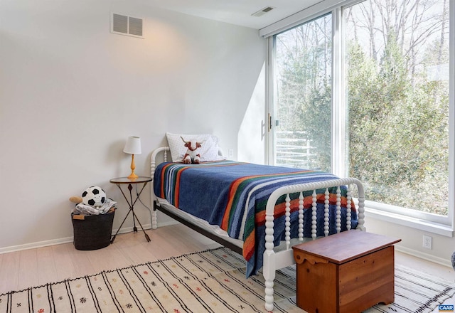 bedroom featuring wood finished floors, baseboards, and visible vents