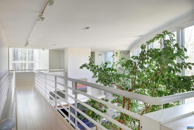 hallway featuring visible vents, an upstairs landing, hardwood / wood-style floors, and rail lighting