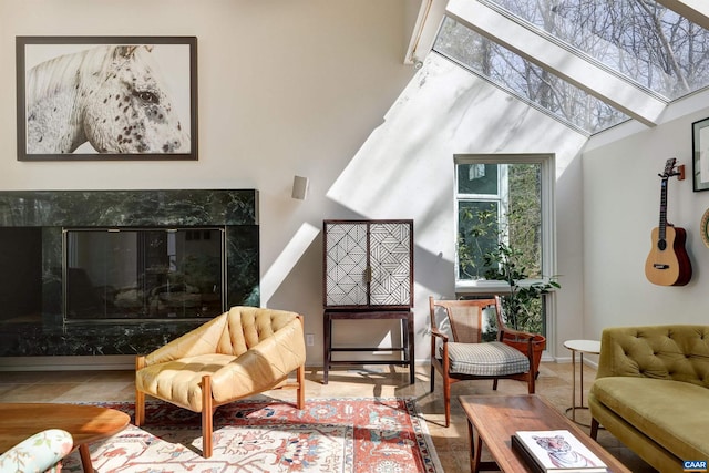 living room with a skylight, a high ceiling, baseboards, and a premium fireplace