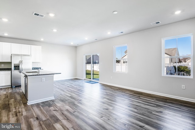 kitchen featuring visible vents, stainless steel fridge, a center island with sink, and a healthy amount of sunlight