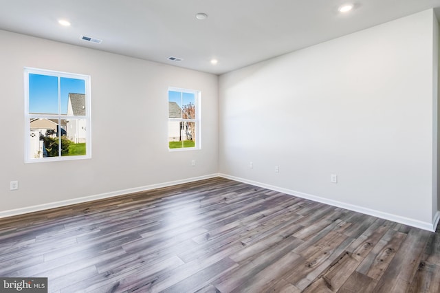 unfurnished room with dark wood finished floors, plenty of natural light, baseboards, and visible vents