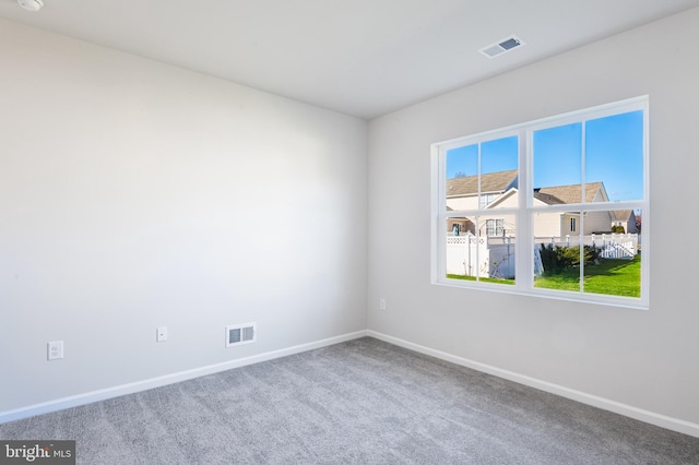 spare room featuring baseboards, visible vents, and carpet floors