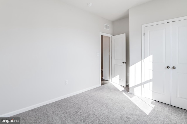 unfurnished bedroom featuring carpet flooring, baseboards, visible vents, and a closet