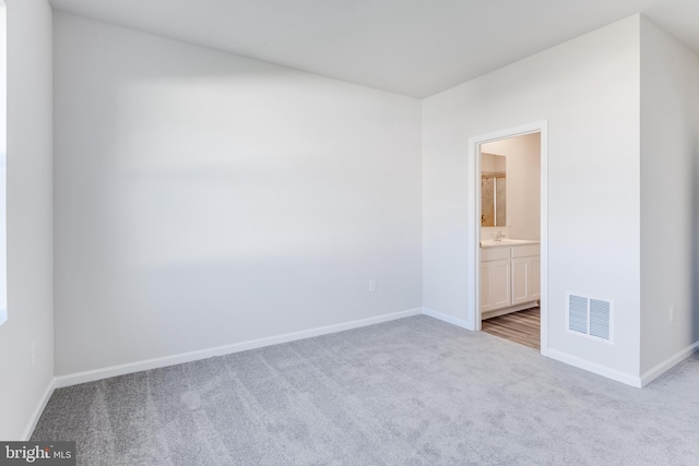 unfurnished room with a sink, visible vents, carpet floors, and baseboards