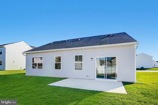 back of house with a yard, a shingled roof, and a patio