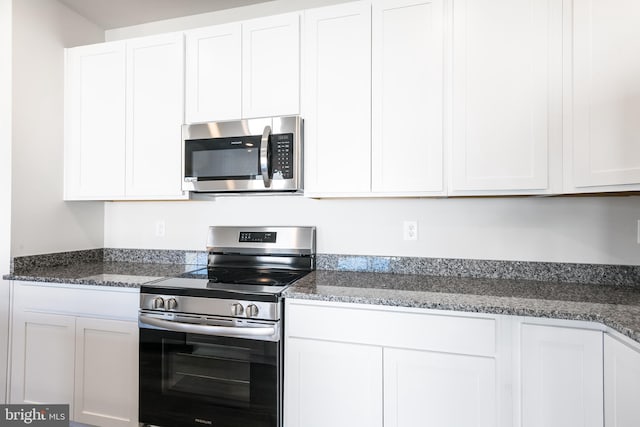 kitchen featuring dark stone counters, appliances with stainless steel finishes, and white cabinetry