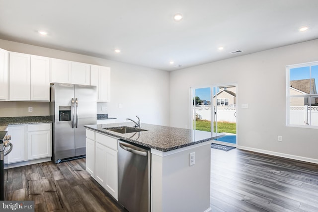 kitchen featuring visible vents, a sink, dark stone counters, appliances with stainless steel finishes, and dark wood-style flooring