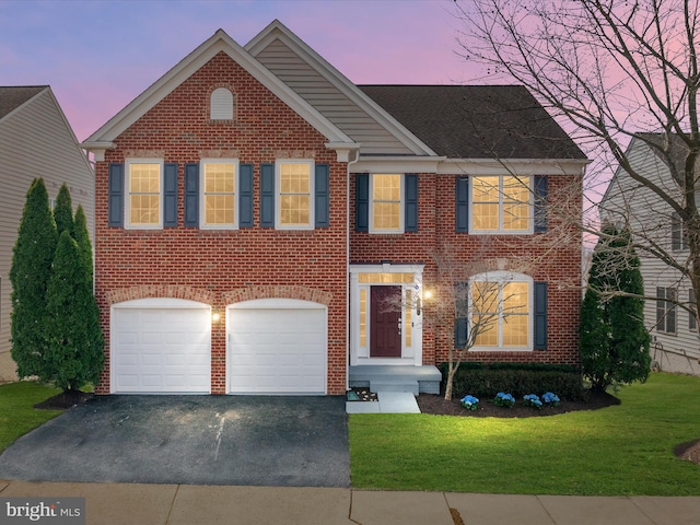 view of front of property featuring aphalt driveway, a garage, a yard, and brick siding