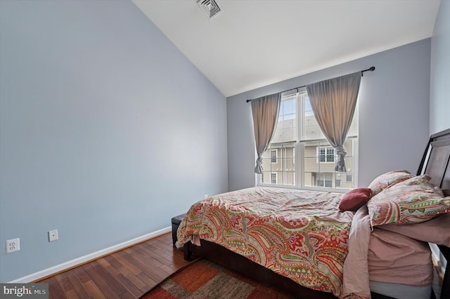 bedroom with baseboards, vaulted ceiling, wood finished floors, and visible vents