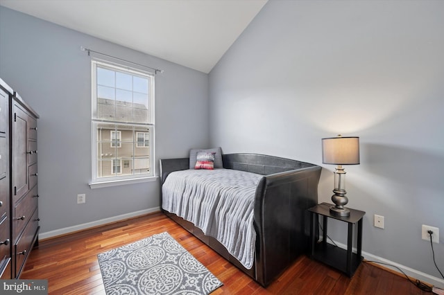 bedroom with baseboards, wood finished floors, and lofted ceiling