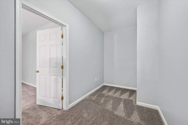 carpeted spare room with baseboards and lofted ceiling
