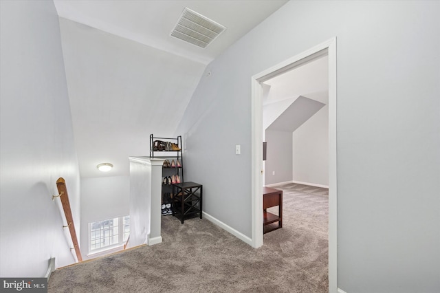 hallway with visible vents, carpet, vaulted ceiling, and an upstairs landing
