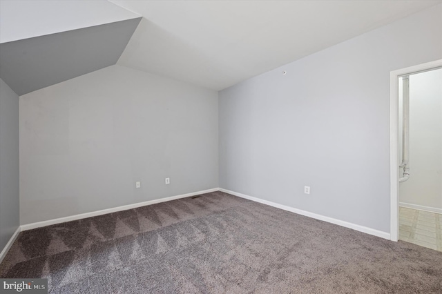 additional living space with baseboards, vaulted ceiling, and carpet