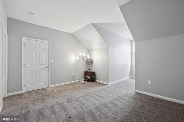 additional living space featuring carpet flooring, baseboards, and vaulted ceiling