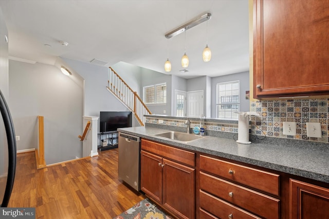 kitchen with a sink, dark countertops, stainless steel dishwasher, and dark wood-type flooring