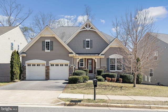 craftsman house with a front yard, roof with shingles, stone siding, driveway, and a standing seam roof