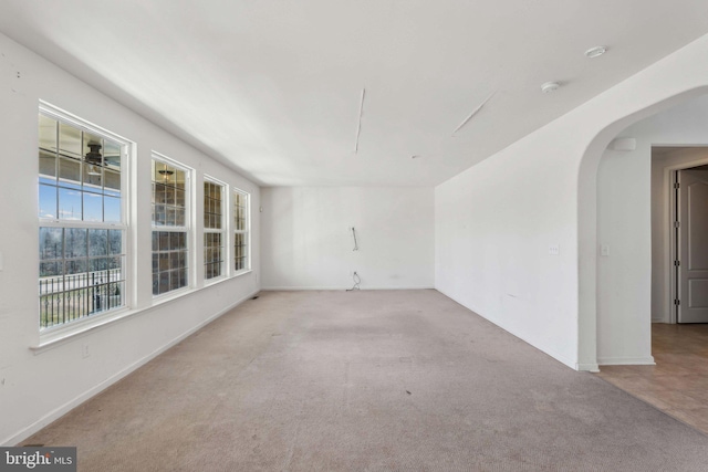 unfurnished room with carpet flooring and arched walkways