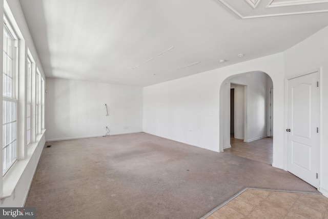 spare room featuring light carpet and arched walkways