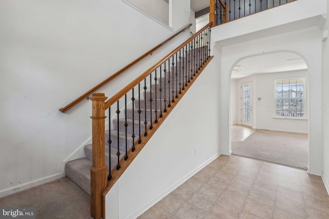 stairway with baseboards, arched walkways, and carpet floors