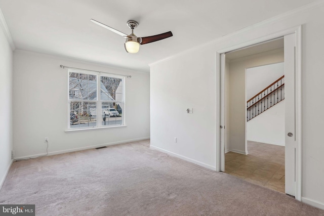 spare room with a ceiling fan, crown molding, carpet, and baseboards