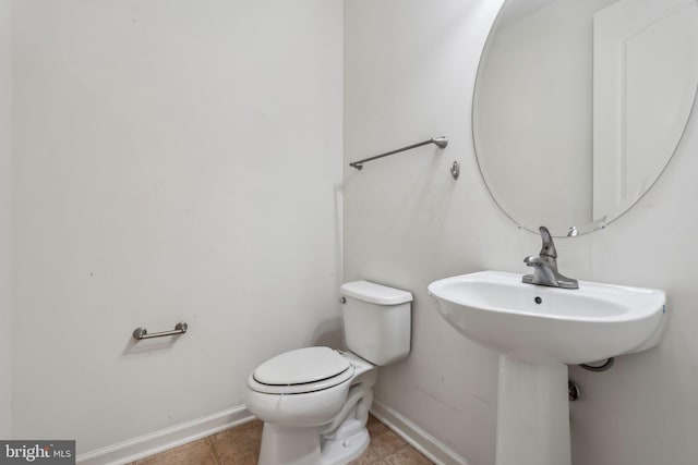 half bathroom featuring tile patterned floors, baseboards, and toilet