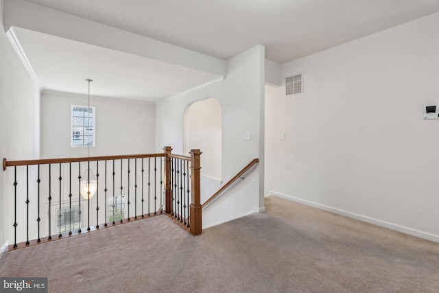 hall featuring visible vents, an upstairs landing, ornamental molding, carpet, and baseboards