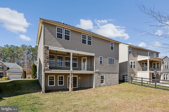 back of house featuring a yard, a balcony, a ceiling fan, and fence