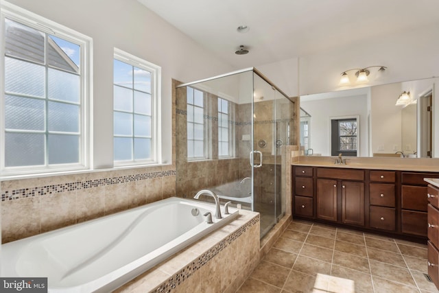 bathroom with double vanity, plenty of natural light, a sink, a shower stall, and a garden tub