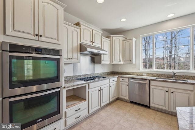 kitchen with light stone counters, recessed lighting, a sink, appliances with stainless steel finishes, and under cabinet range hood