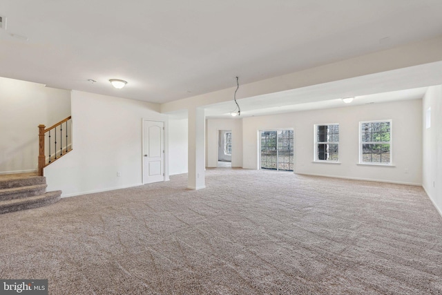 unfurnished living room featuring carpet flooring, visible vents, stairs, and baseboards