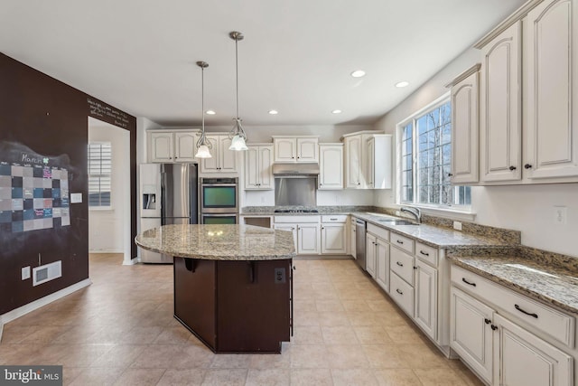 kitchen featuring under cabinet range hood, a sink, a kitchen island, stainless steel appliances, and light stone countertops