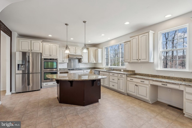 kitchen with visible vents, a center island, light stone countertops, appliances with stainless steel finishes, and a sink