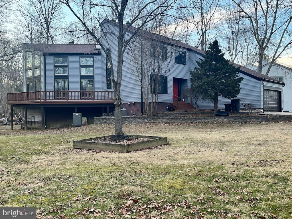 view of front of home featuring a front lawn, a garage, and a wooden deck